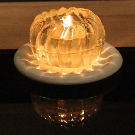 Auf weißem Kerzen-Keramikteller gelbliche Edelstein Spiralkugelkerzen.
